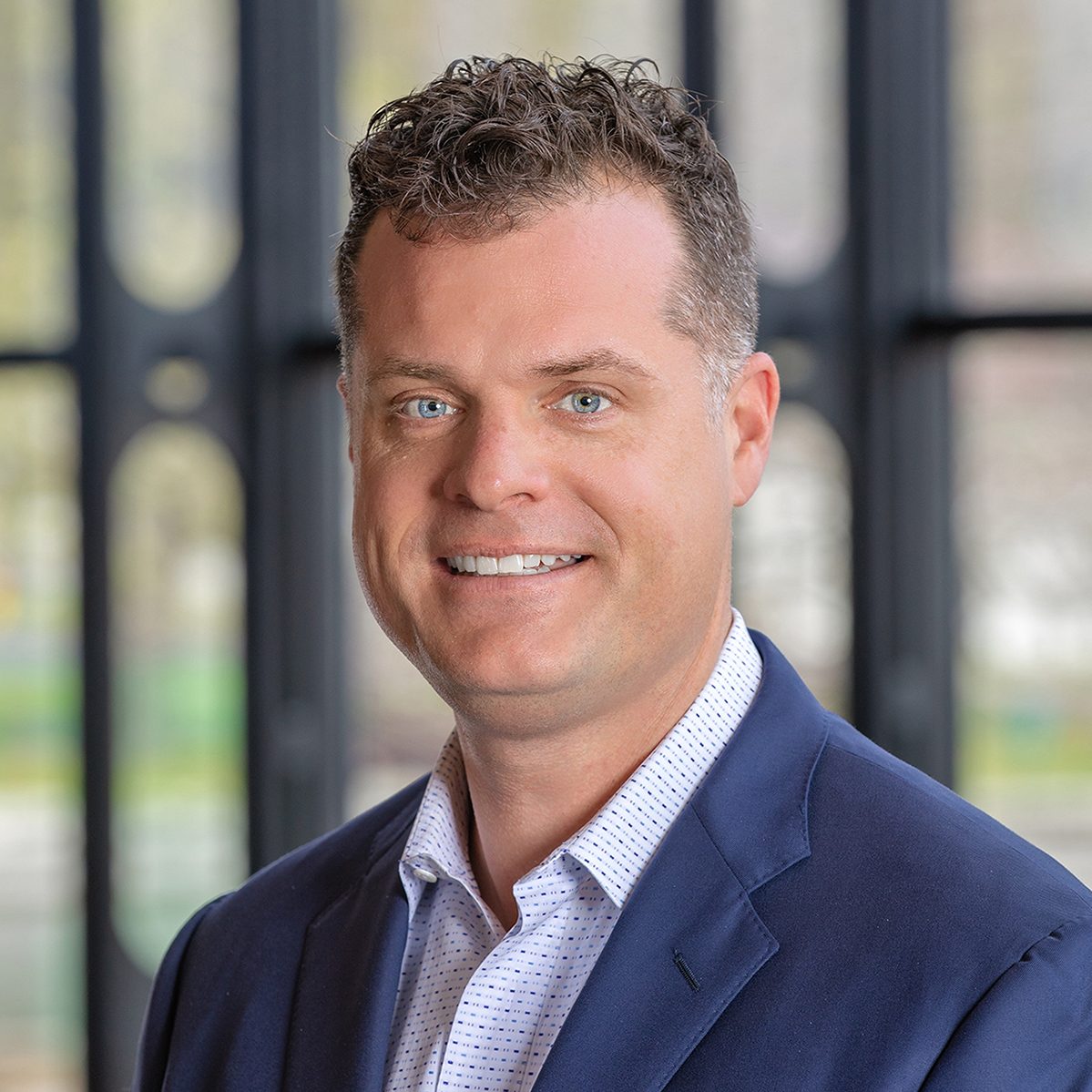 Bryan Taylor headshot with windows and natural light in the background