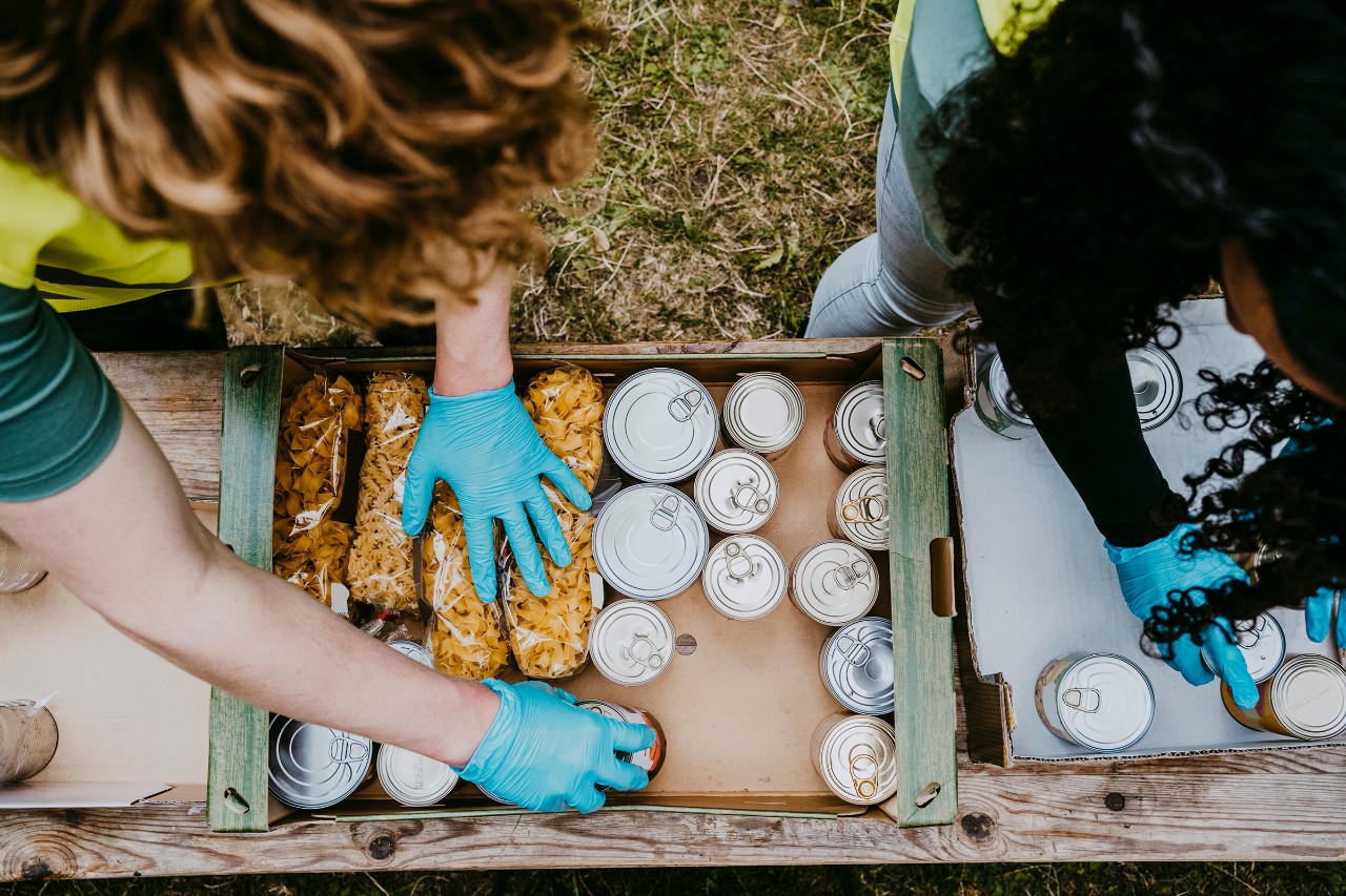 Hands with blue gloves grabbing cans of food
