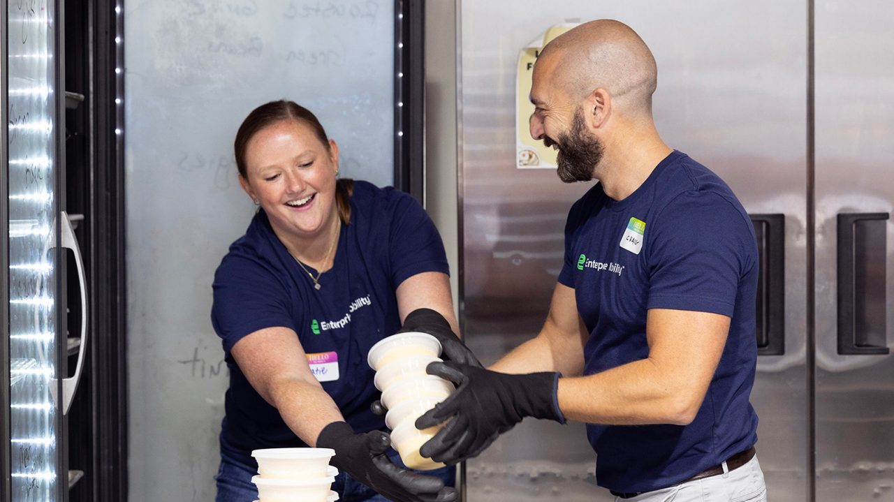 A male and female team member handle food at a food pantry