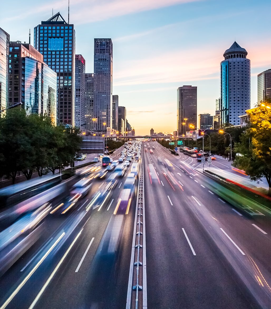 Image of a road with fast cars in a downtown setting