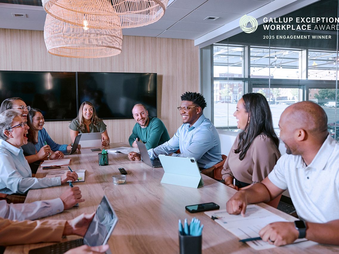 Several people sitting at a conference table and laughing during a business meeting