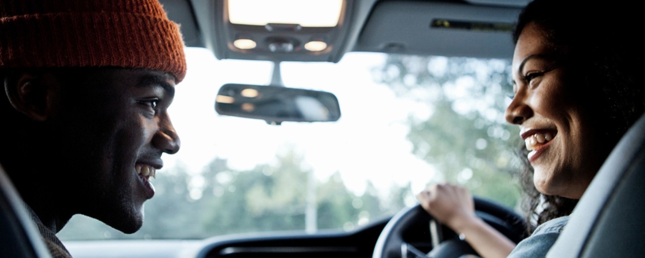 A man and woman in the United Kingdom talk inside a car