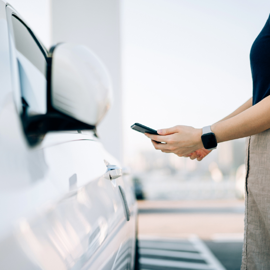 Woman uses her cell phone to open a car door
