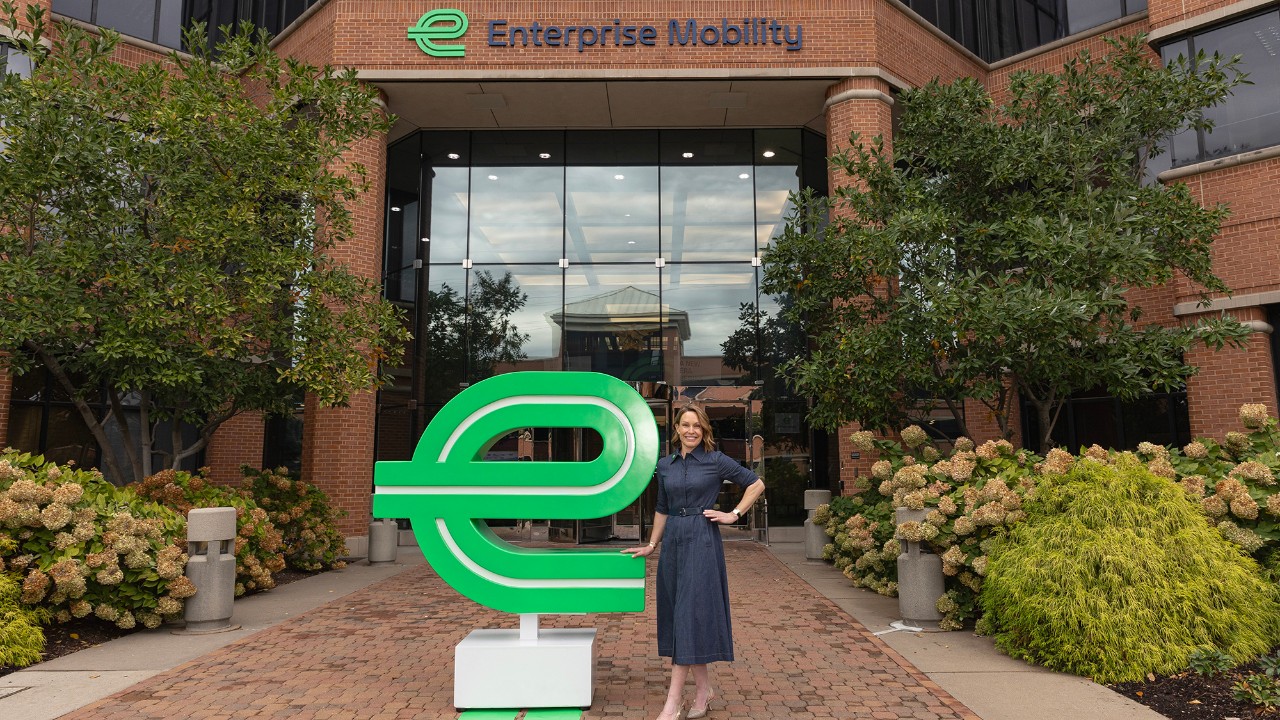 President & CEO Chrissy Taylor, smiling and with her arms folded, in front of a building on the Enterprise Mobility corporate campus in St. Louis.