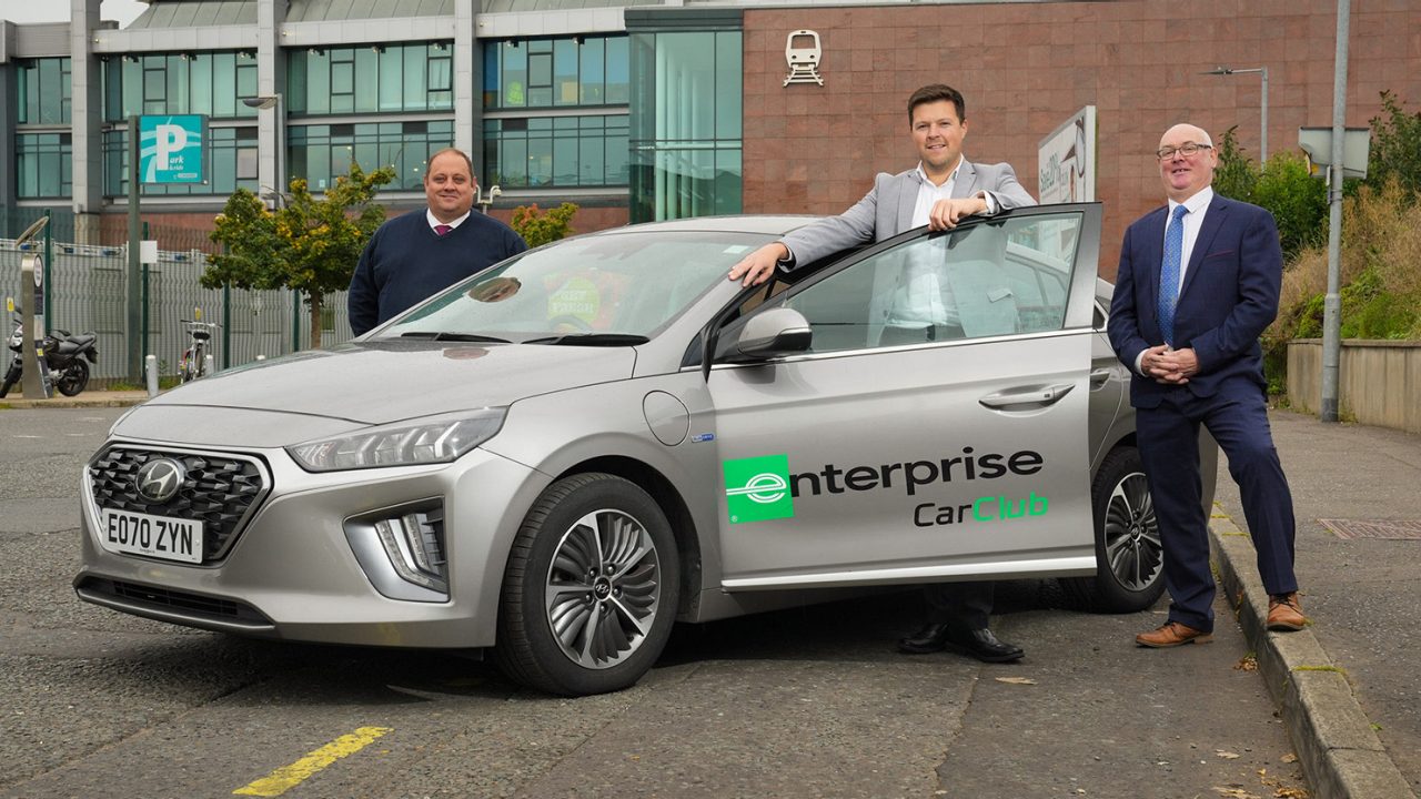 Three middle-aged males standing around a silver Car Club vehicle.