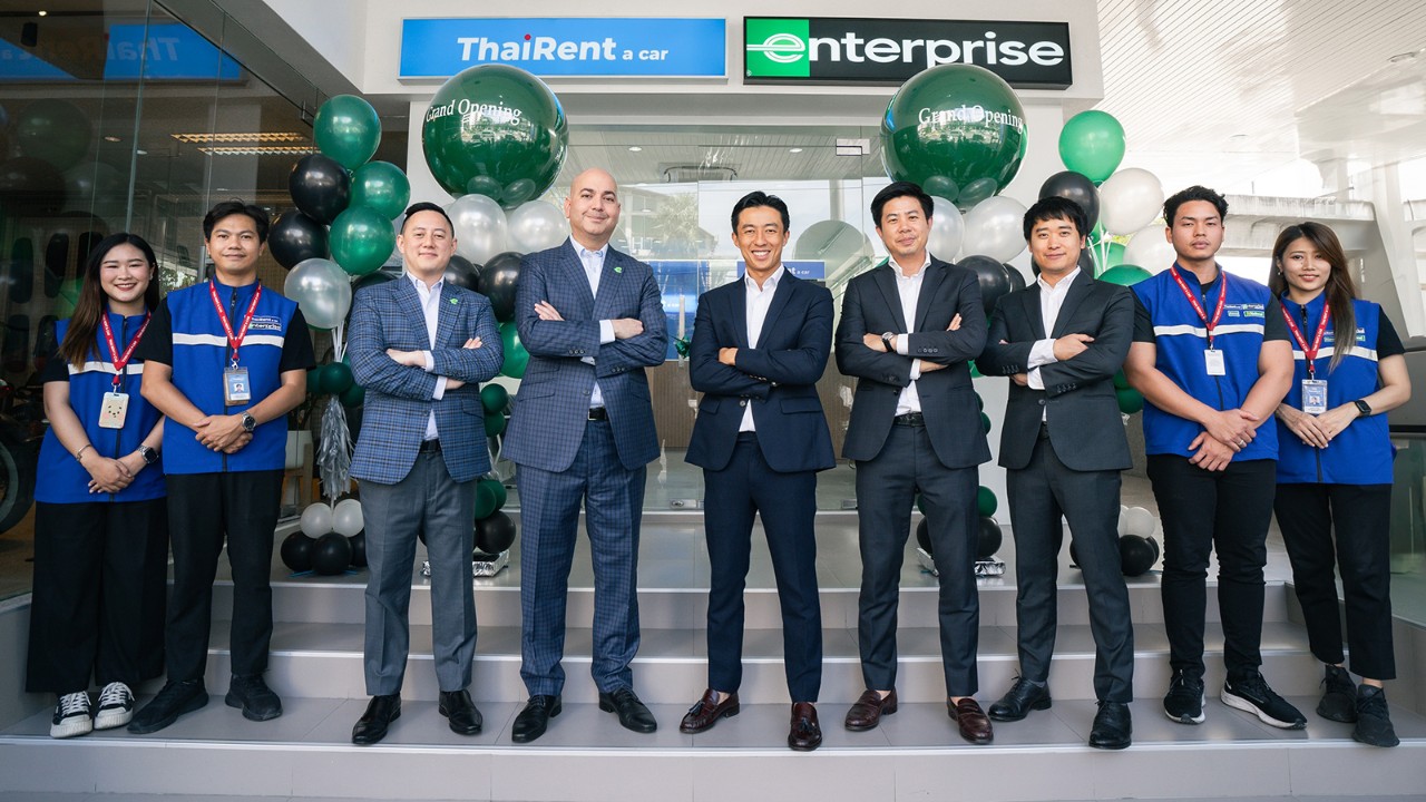 Several employees standing in front of new location desk with signage and balloons in the background