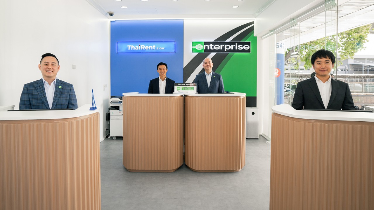 Four gentlemen standing behind desks at newest location in Thailand