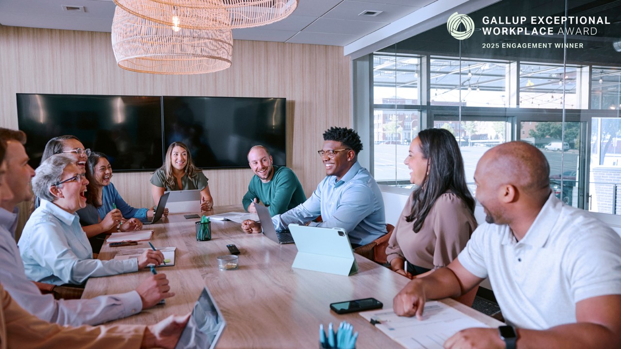 Several people sitting at a conference table and laughing during a business meeting