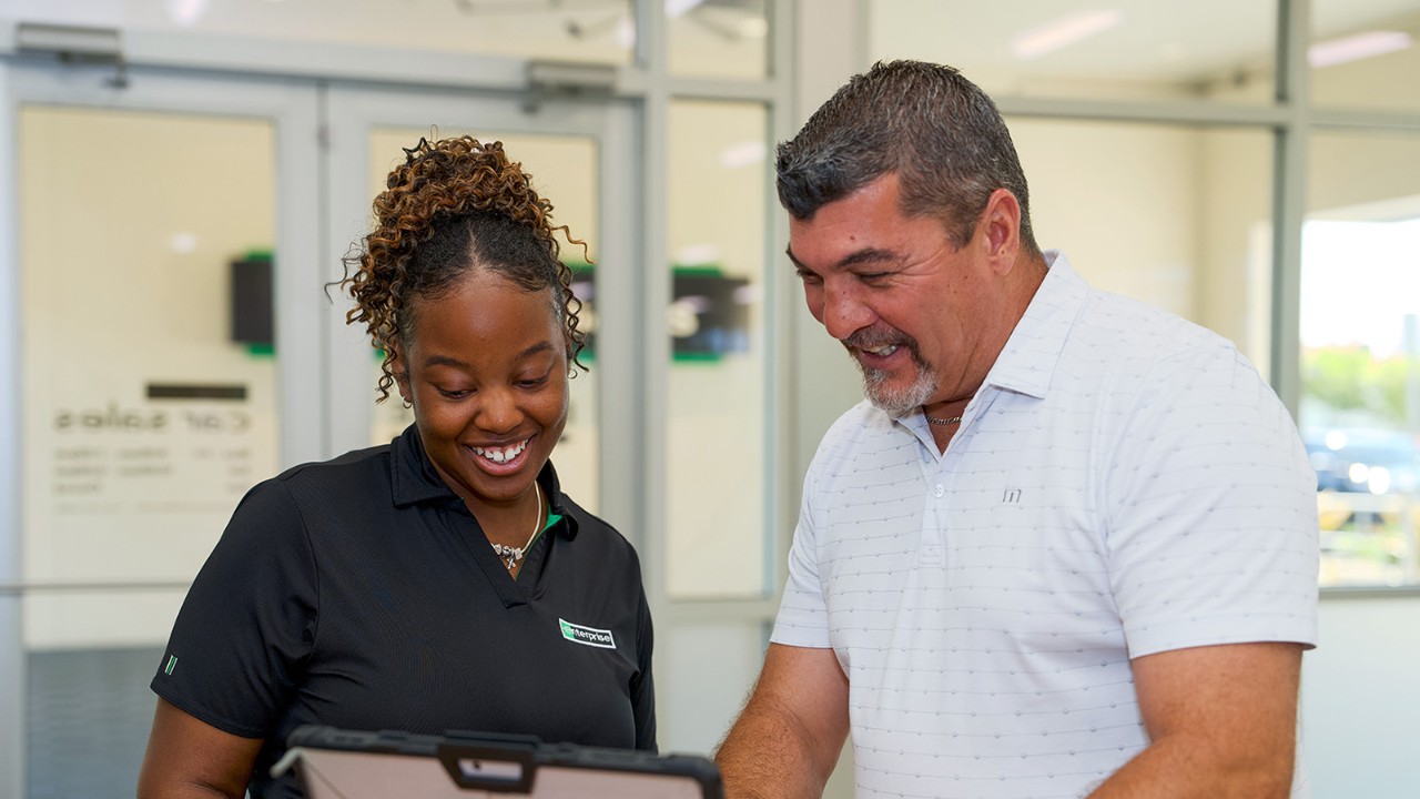One male and one female employee talk and laugh inside a rental branch