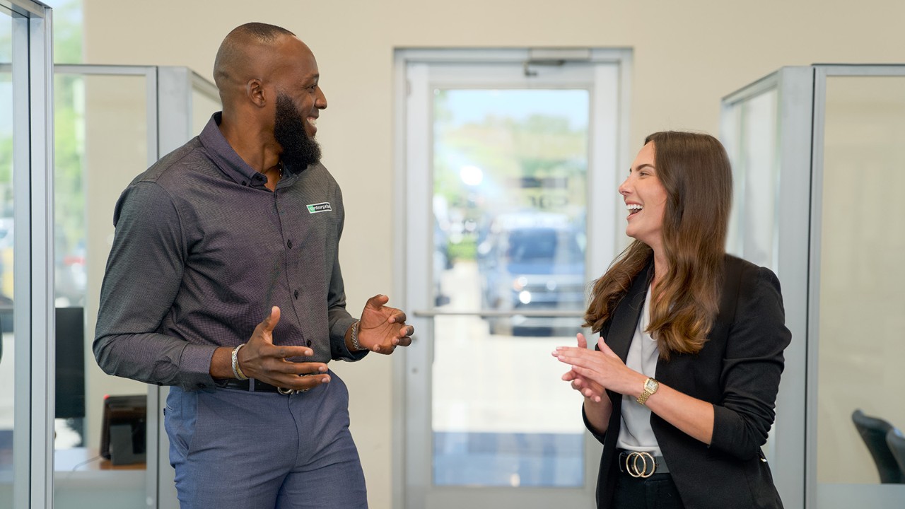One male and one female employee talk and laugh inside a rental branch