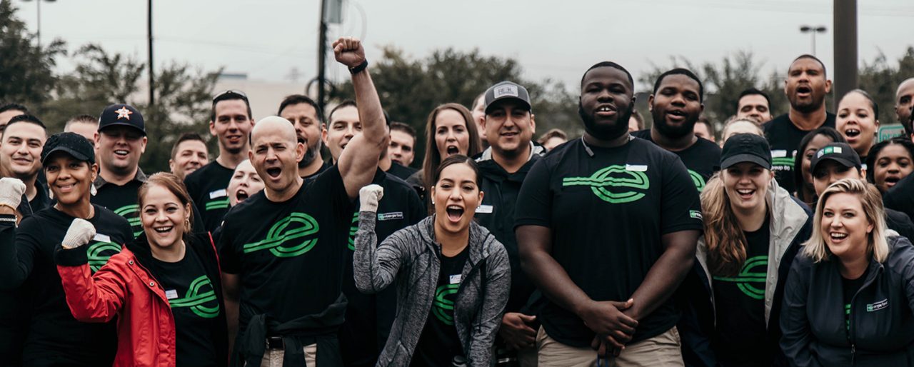 Severl people in black Enterprise t-shirts pumping their firsts and showing excitement