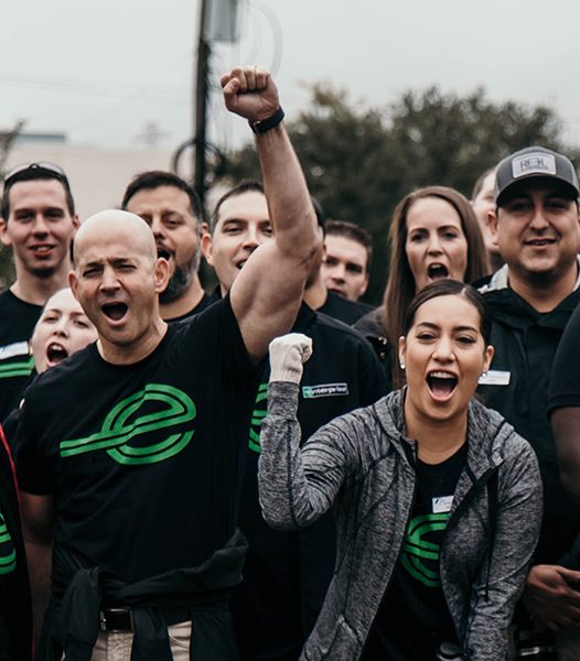 Severl people in black Enterprise t-shirts pumping their firsts and showing excitement