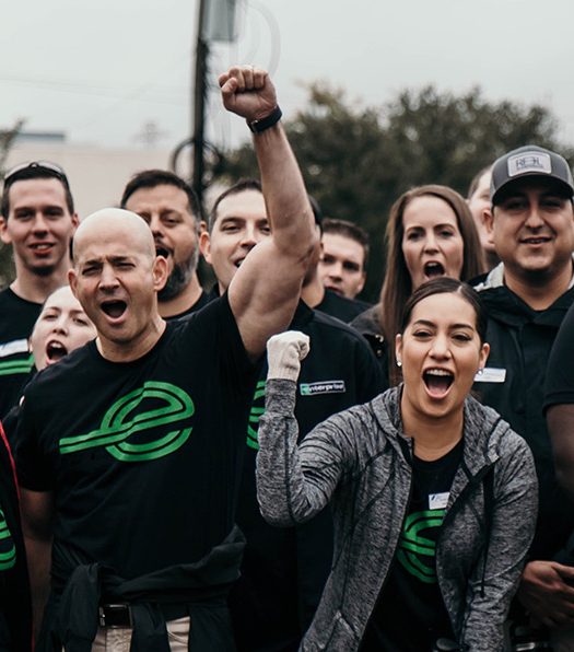  Severl people in black Enterprise t-shirts pumping their firsts and showing excitement