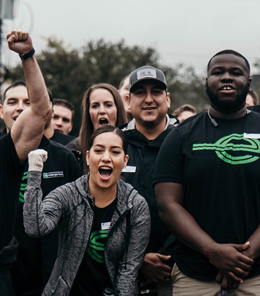 Severl people in black Enterprise t-shirts pumping their firsts and showing excitement