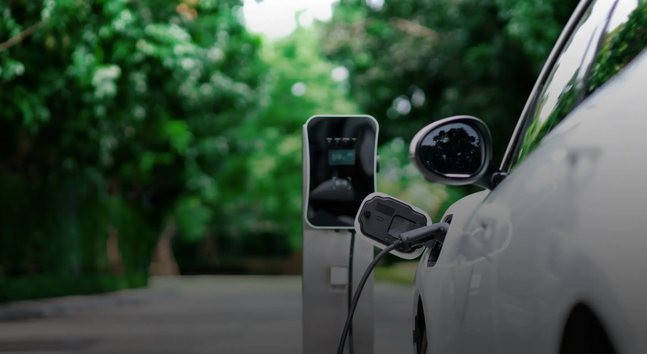 Un vehículo eléctrico blanco conectado a una estación de carga.